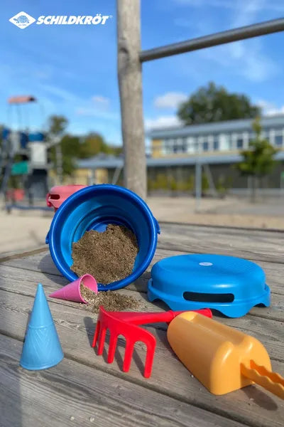 Set de jouets de sable 7-en-1 Schildkröt en version bleue - mise en situation à la plage : seau déplié avec du sable, pelle, râteau, tamis et moules.