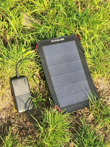Chargeur solaire ultraléger et compact de Sunslice- mise en situation sur l'herbe du Flex 6W qui charge un GSM