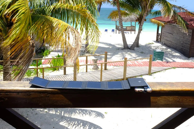 Chargeur solaire Photon de Sunslice – mise en situation : déplié sur la rambarde d’un balcon surplombant une plage
