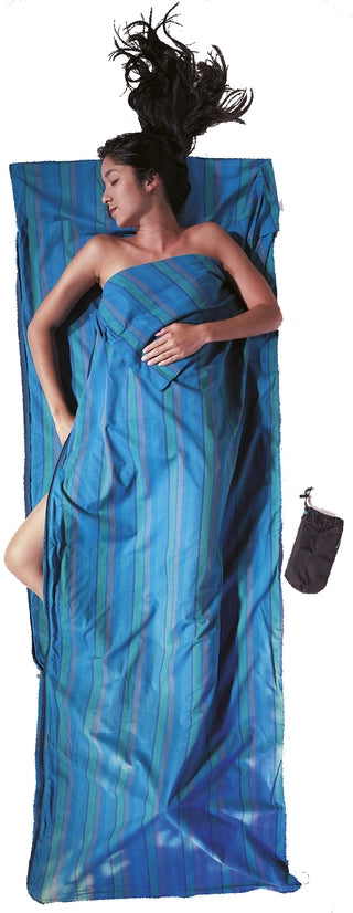 Housse de lit zippée en coton de Cocoon - bleu - Mise en situation : une personne dort avec une jambe sortie de la housse de lit avec la pochette posée à côté, utilisée en version simple