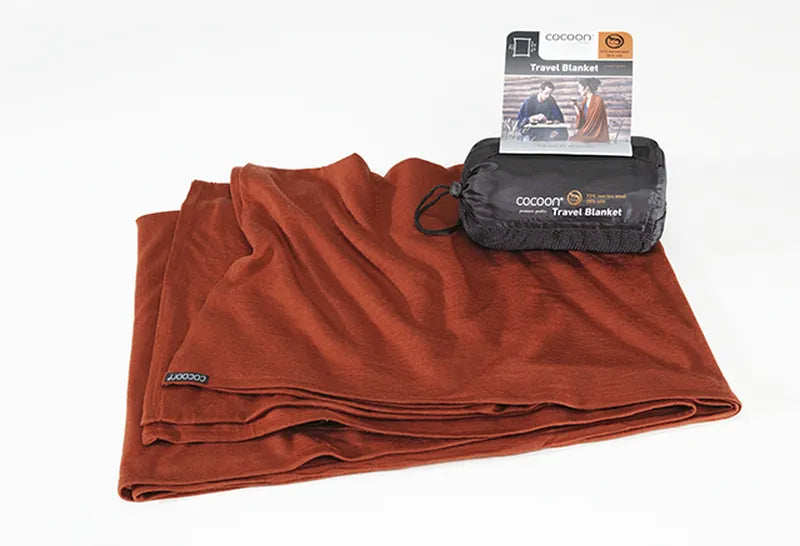 Couverture de voyage en laine et soie – terracotta – vue de la couverture pliée, avec son sac de rangement posé dessus.