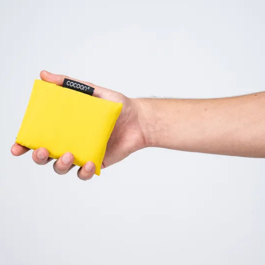 Nappe de pique-nique Cocoon – présentée pliée dans sa pochette, portée à la main.