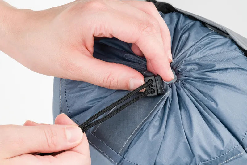 Sac de compression ultraléger – gros plan sur le système de fermeture coulissant, avec deux mains en train de refermer le sac.