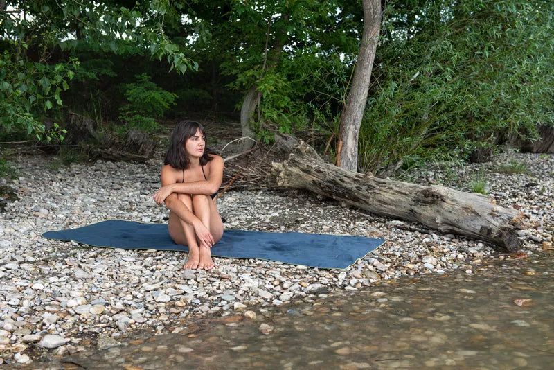 Poncho-serviette unisexe de Cocoon - Mise en situation : une dame est installée sur le poncho-serviette