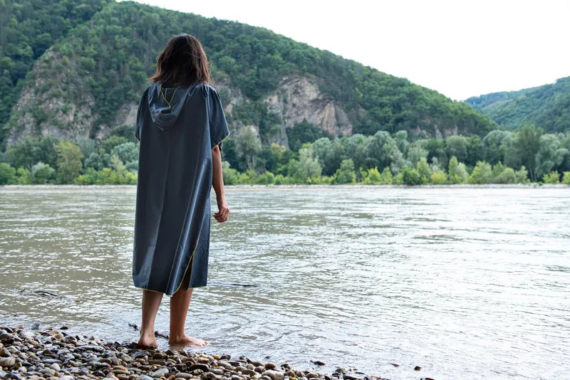Poncho-serviette unisexe de Cocoon - vue de dos, porté par une dame devant un lac