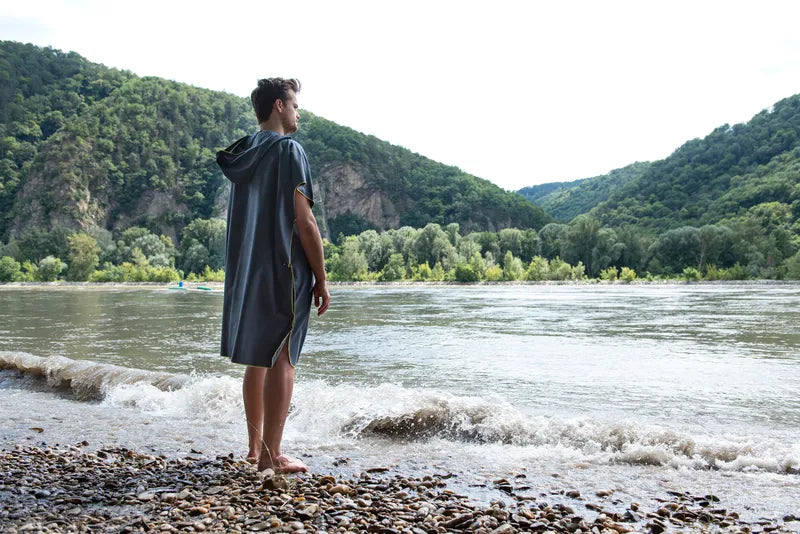 Poncho-serviette unisexe de Cocoon - vue de dos, porté par un homme devant un lac