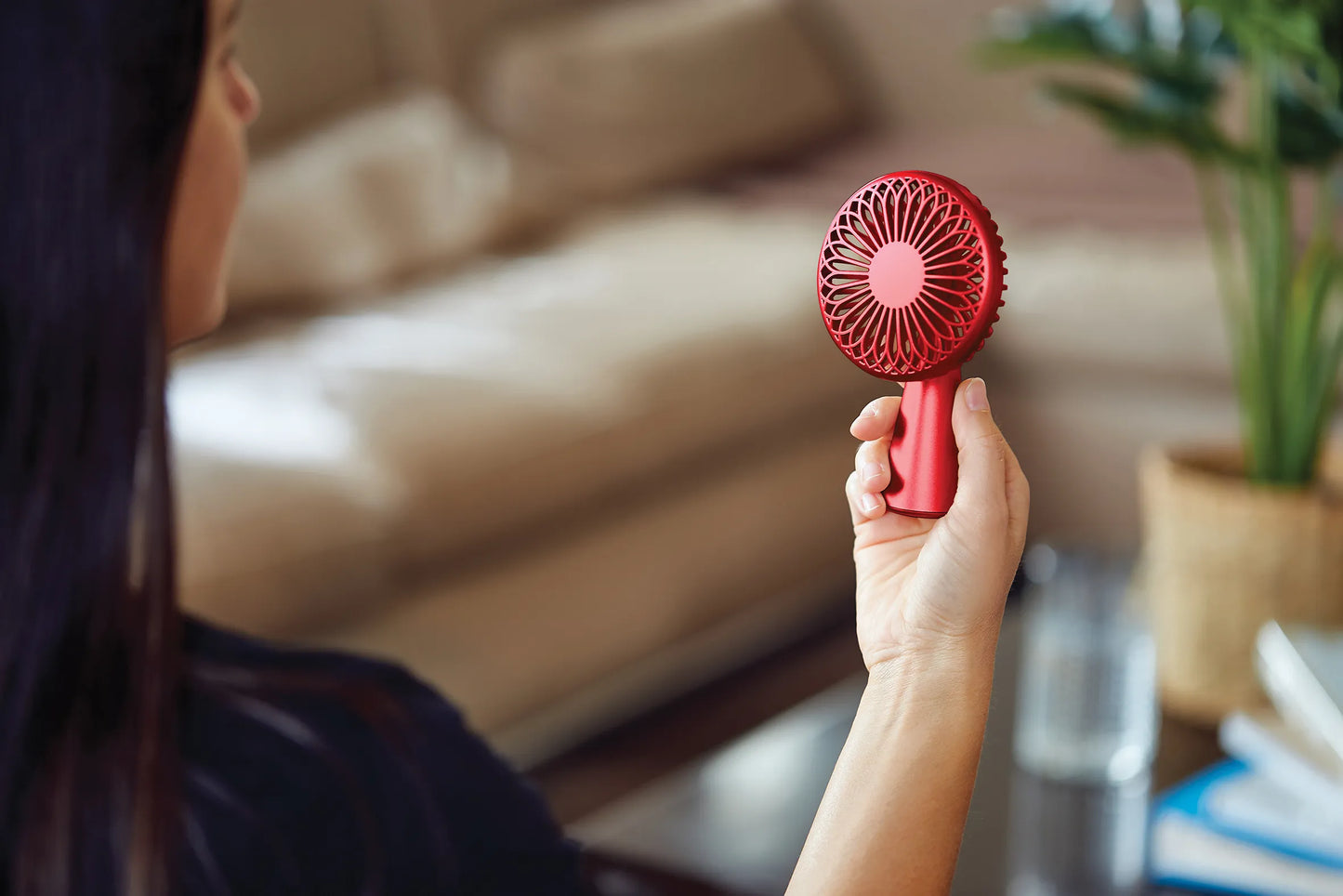 Ventilateur portatif rouge Lexon tenue par une main devant un visage