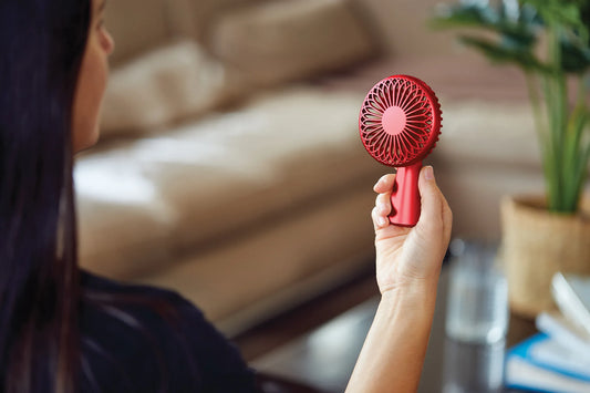 Ventilateur portatif rouge Lexon tenue par une main devant un visage