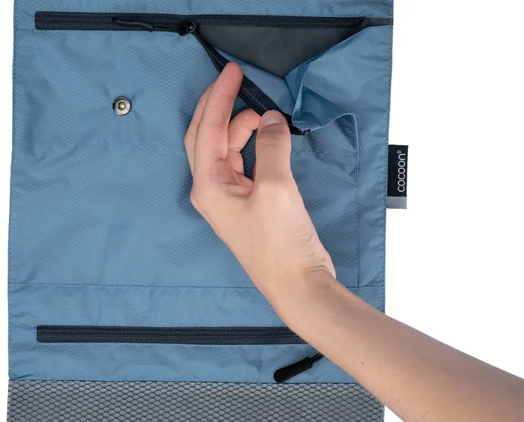 Trousse de toilette accrochable Cocoon – bleu – gros plan sur une pochette ouverte par une main