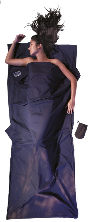 Housse de lit adulte en coton Egyptien de Cocoon - Marine - Housse de lit adulte en coton et soie Cocoon – bleu – mise en situation : une personne dort dans le drap, la pochette placée juste à côté.