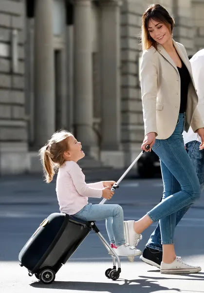 Valise trolley avec siège enfant intégré Micromobility – mise en situation : une femme tire la valise avec une petite fille assise dessus dans la rue