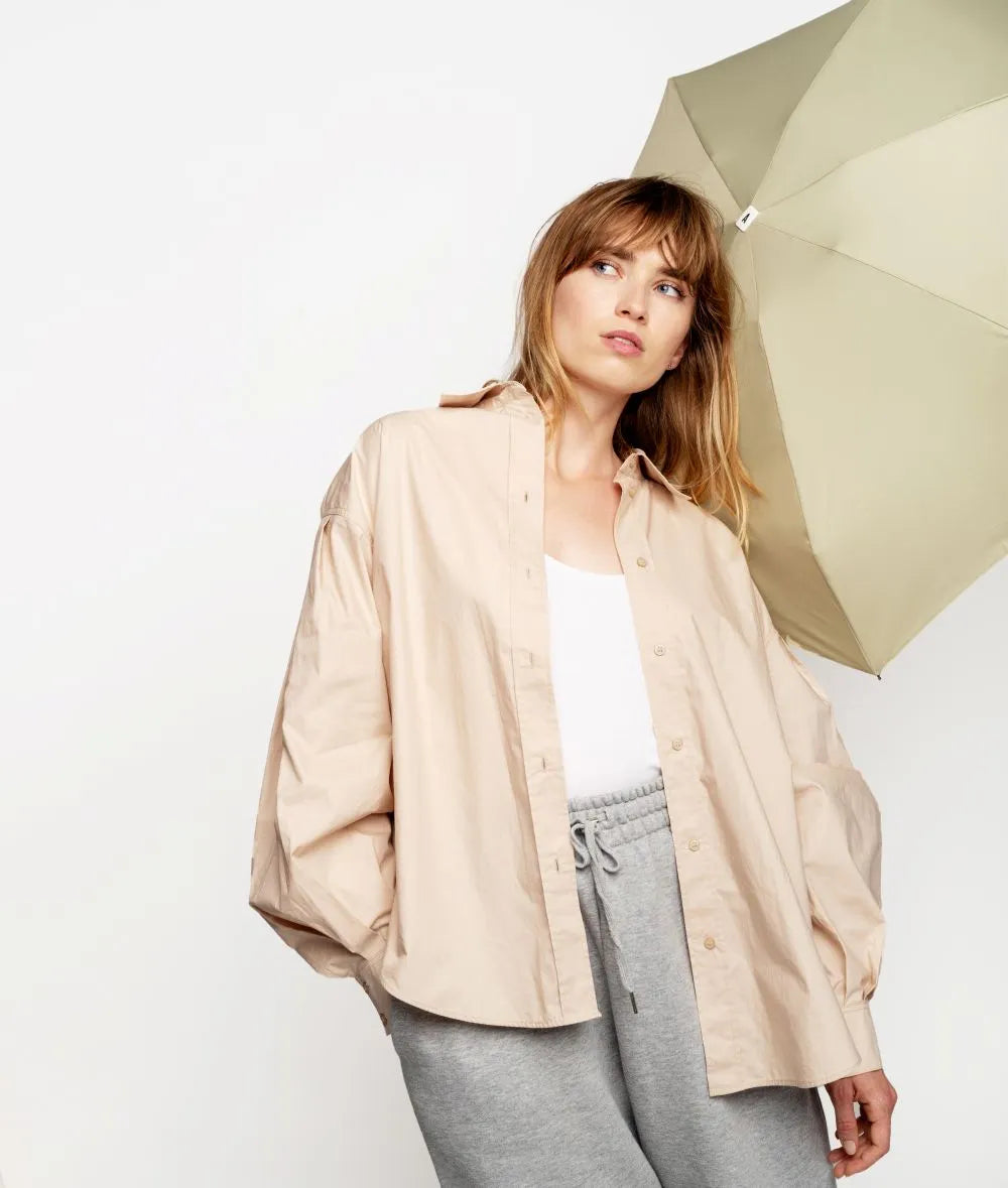 Mini parapluie pliant Anatole - beige - vue de face du parapluie ouvert derrière une dame