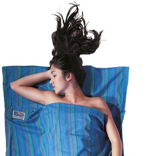 Housse de lit zippée en coton de Cocoon - bleu - Mise en situation : une personne dort dans la housse de lit avec la pochette posée à côté, utilisée en version simple