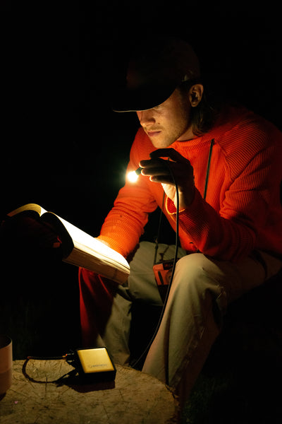 Câble multi-connecteurs Waka Waka Connect – Mise en situation : une personne lit un livre dans le noir grâce à la lumière LED intégrée au câble