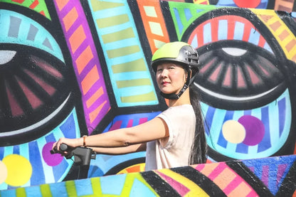 Couvre-casque jaune amovible pour casque PLIXI FIT – mise en situation : porté par une femme roulant en trottinette