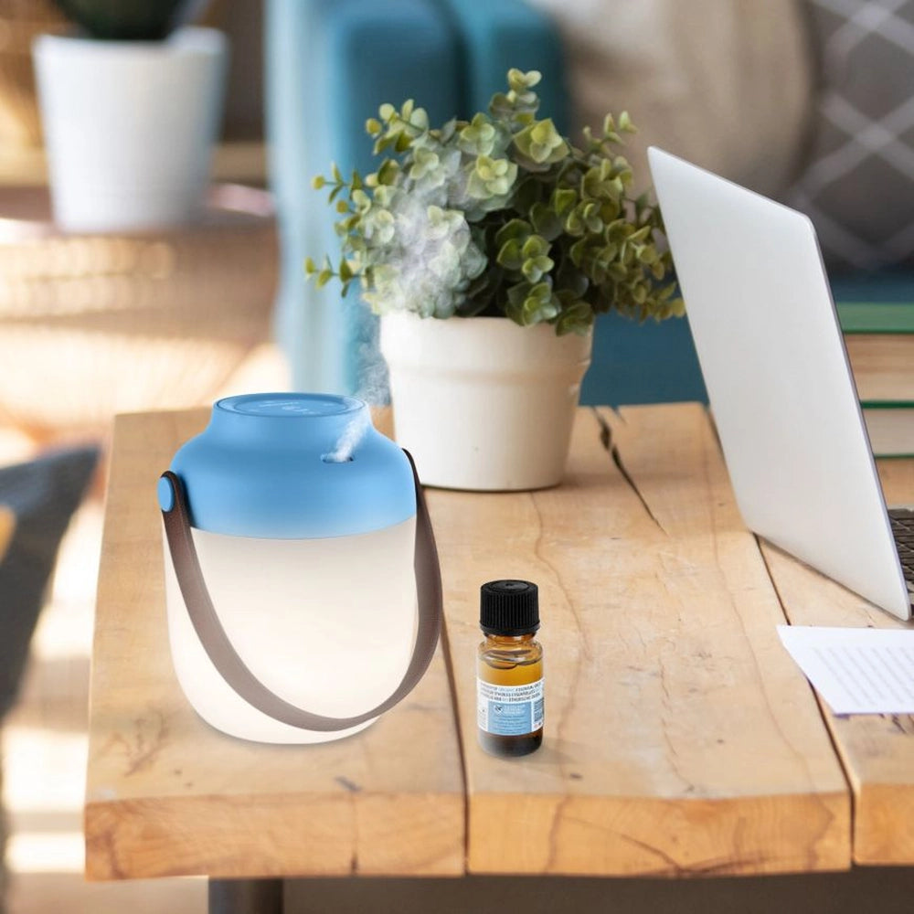 Diffuseur d’huiles essentielles et lanterne portable – mise en situation avec le système de diffusion actif sur une table d'extérieure et avec un flacon d'huile essentielle