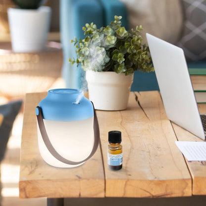Diffuseur d’huiles essentielles et lanterne portable – mise en situation avec le système de diffusion actif sur une table d'extérieure et avec un flacon d'huile essentielle