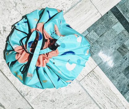 Tapis de jeu et sac de rangement d’extérieur Play and Go – motif jeux – vue du sac en version rangement sur le bord d'une piscine