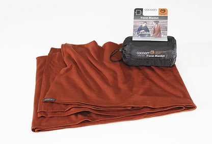Couverture de voyage en laine et soie – terracotta – vue de la couverture pliée, avec son sac de rangement posé dessus.