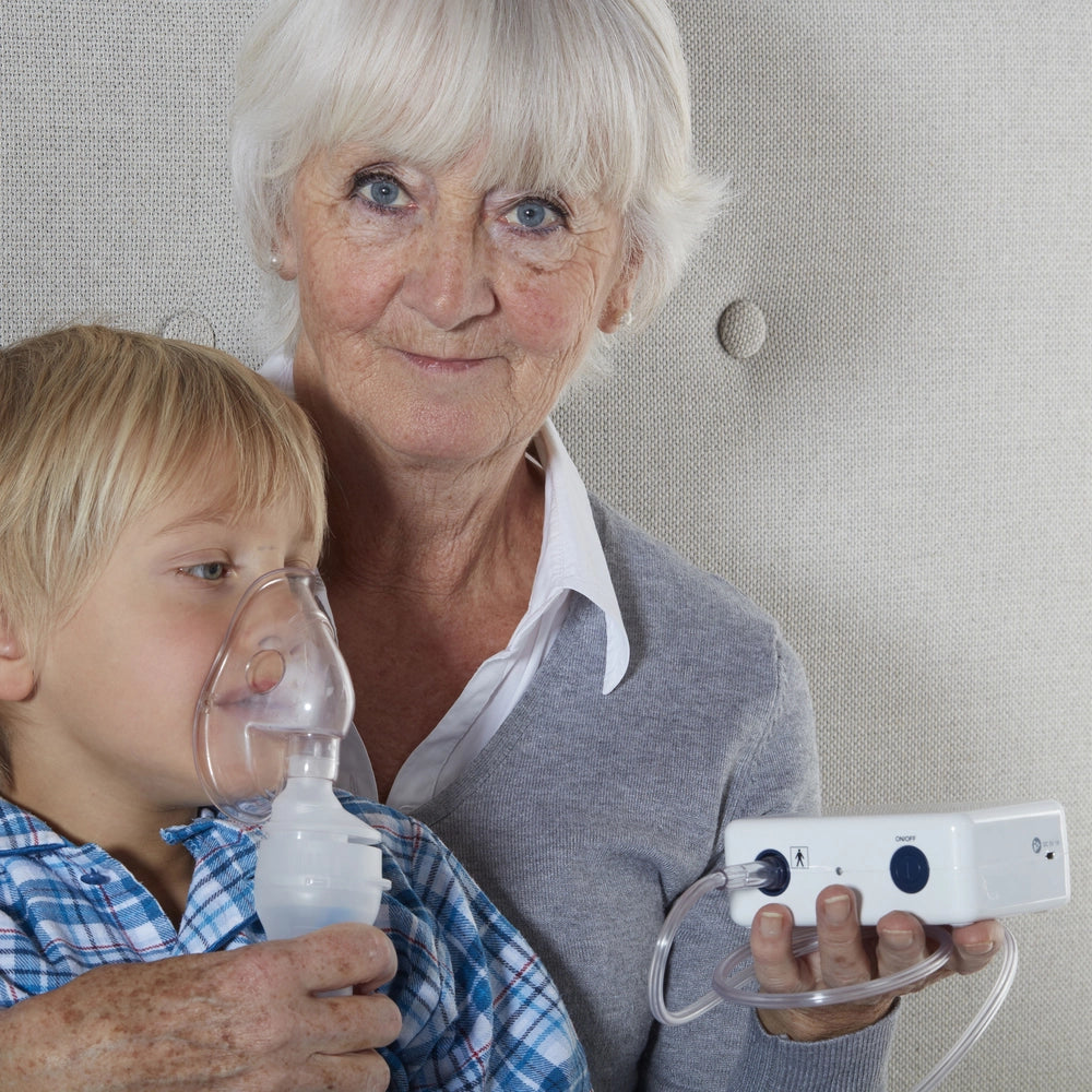 Aérosol compact en utilisation par une dame tenant d'une main l'aérosol et de l'autre plaçant le masque sur la bouche et le nez d'un enfant