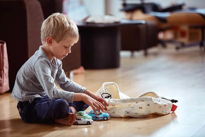 Mini sac de rangement et tapis de jeux motif voitures de Playandgo - vue du sac ouvert et un garçon qui joue avec des voitures à coté du sac