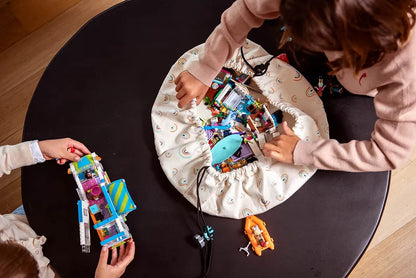 Mini sac de rangement et tapis de jeux motif arc-en-ciel de Playandgo - vue du sac ouvert avec des jeux sur une table et des enfants qui jouent