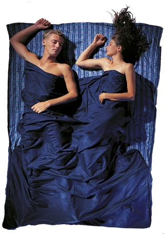 Housse de lit zippée en soie de Cocoon – motif à carreaux bleus en soie – mise en situation : deux personnes dorment dans la housse, utilisée en version double
