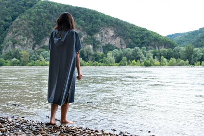 Poncho-serviette unisexe de Cocoon - vue de dos, porté par une dame devant un lac