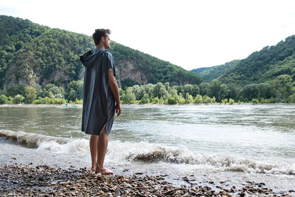 Poncho-serviette unisexe de Cocoon - vue de dos, porté par un homme devant un lac