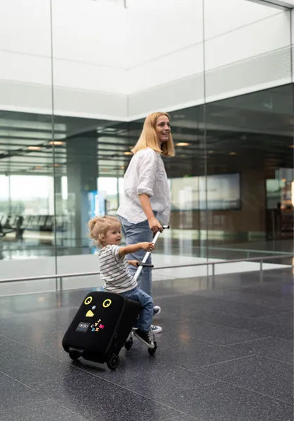 Valise trolley avec siège enfant intégré Micromobility – mise en situation : une femme tire la valise avec une petite fille assise dessus dans un aéroport
